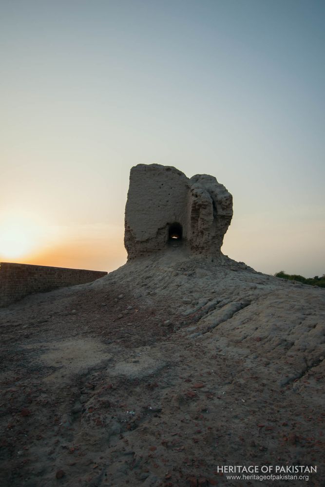 Watchtower silhouette frames the golden hour over the mound.